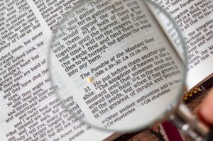 Close up of the parable of the mustard seed in the Bible with a magnifying glass. By Marinela/stock.adobe.com